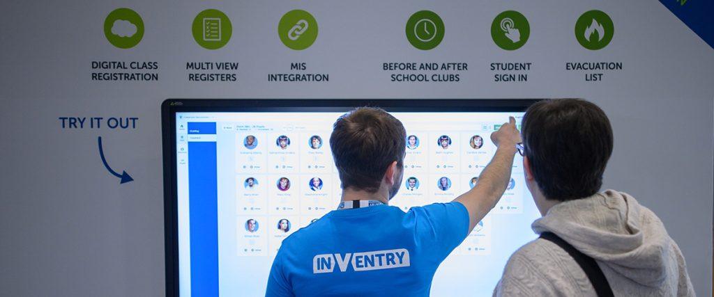 Person at a trade show using an InVentry system on a large touch screen.