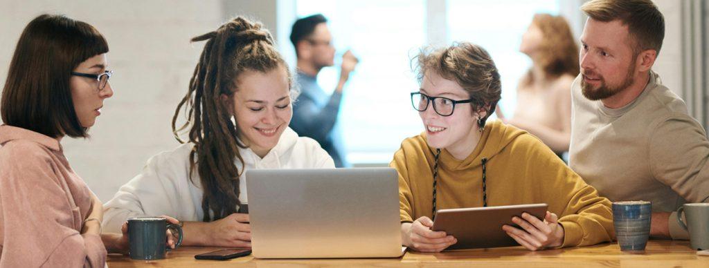 People leaning on a table looking at a laptop screen