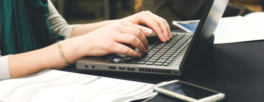 Person typing on a laptop keyboard.