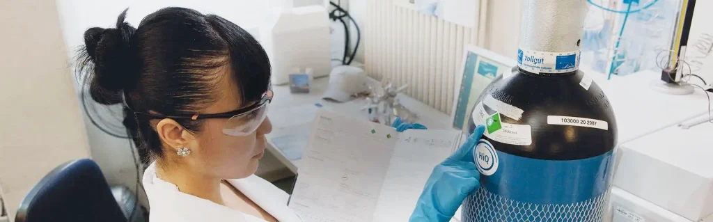 Scientist in lab checking a gas canister.