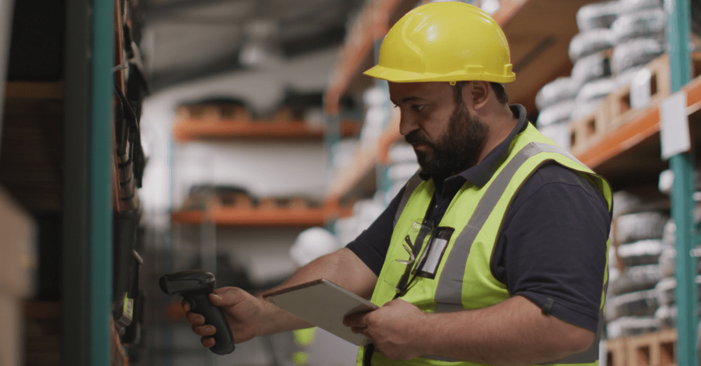 Man in hard hat scanning boxes in warehouse